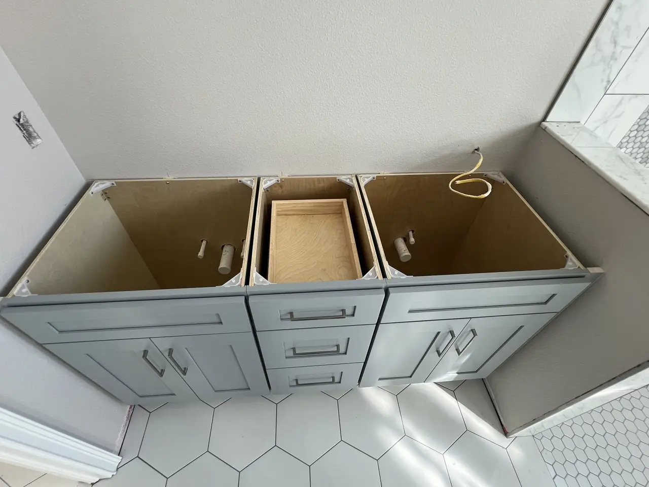Sage-gray shaker vanity cabinets set and leveled in a Tampa Bay home